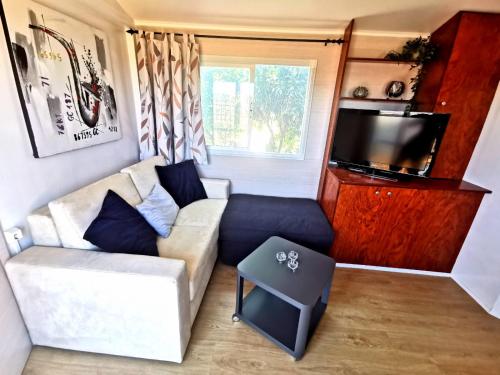 a living room with a couch and a tv at Casa Azul-Tiny house with fantastic view, big outdoor space and pool in Silves