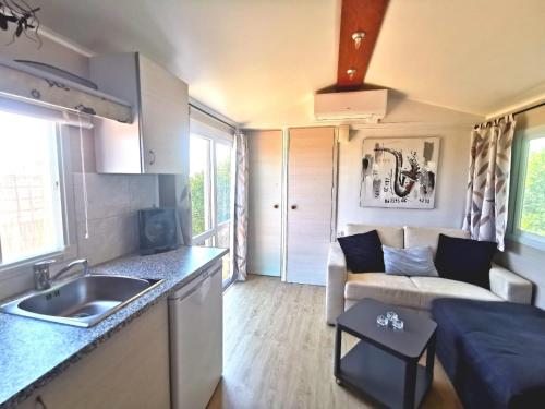 a kitchen and living room with a sink and a couch at Casa Azul-Tiny house with fantastic view, big outdoor space and pool in Silves