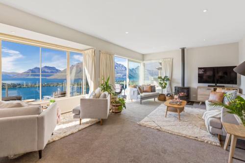 a living room with a view of the water and mountains at Unbeatable Panoramic Lake & Mountain & Garden Views in Queenstown