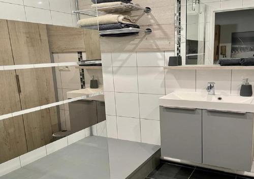 une salle de bain blanche avec un lavabo et un miroir dans l'établissement Welcome Appart Colmar, à Colmar