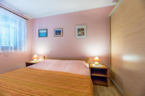 ein Schlafzimmer mit einem Bett und zwei Nachttischen mit Lampen in der Unterkunft Marina in Baška