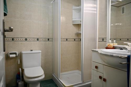 een badkamer met een toilet, een douche en een wastafel bij Bello apartamento con piscina a un paso del centro in Denia