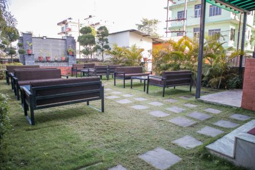 a row of benches sitting in the grass at Mirage Inn in Lumbini