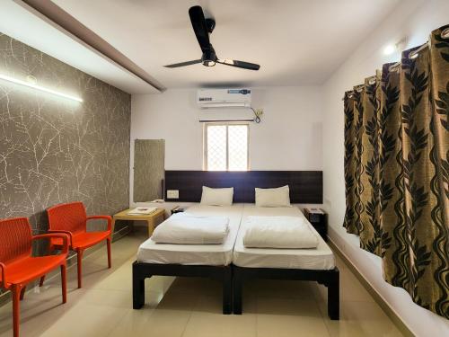 a bedroom with two beds and two orange chairs at Shivani Inn Hotel & Banquet in Seonī