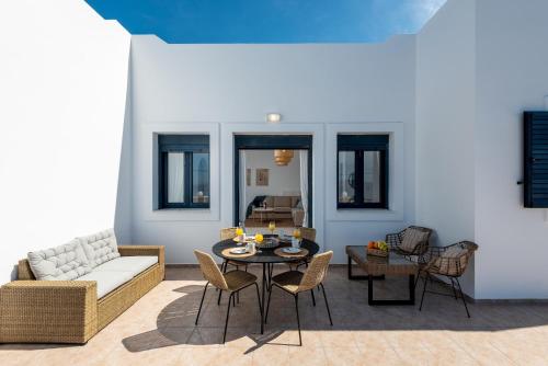 uma sala de estar com um sofá, uma mesa e cadeiras em Sacada Seascape Nisyros em Páloi