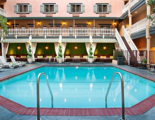 uma grande piscina num hotel com cadeiras e um edifício em Ayres Hotel Costa Mesa Newport Beach em Costa Mesa