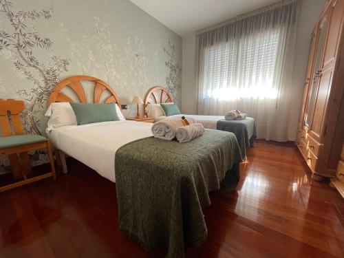 a bedroom with a bed and two tables with towels at Oktheway Rua Nova 3D in Sarria