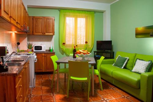 a kitchen with a green couch and a table with chairs at Casa Libertà in Castellammare del Golfo