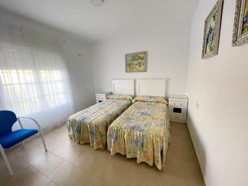 1 dormitorio con 1 cama y 1 silla azul en Chalet en Conil, descansa y disfruta, en Conil de la Frontera