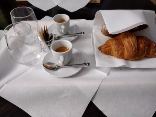 a table with a plate of croissants and cups of coffee at Hotel Ca' di Gali in Sasso Marconi