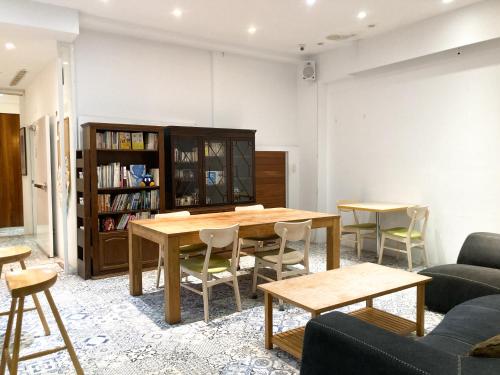 4Plus Hostel في تايبيه: غرفة معيشة مع طاولة وكراسي ورف كتاب