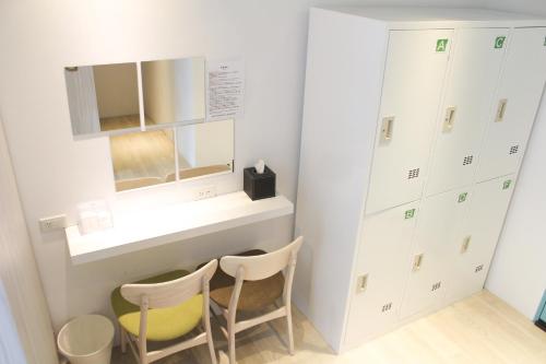a dressing room with two chairs and a mirror at 4Plus Hostel in Taipei