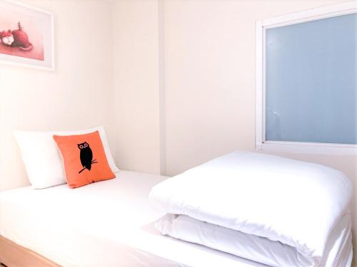 a white bedroom with two beds and a window at 4Plus Hostel in Taipei