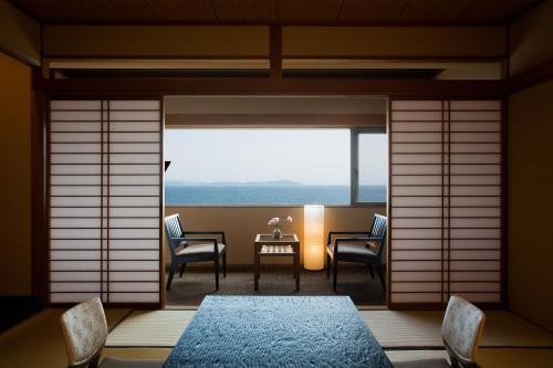 ein Esszimmer mit einem Tisch, Stühlen und einem Fenster in der Unterkunft Awaji International Hotel The Sunplaza in Sumoto