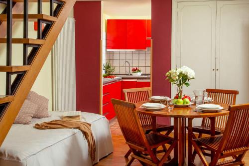una sala da pranzo con tavolo e una cucina con armadi rossi di Bollo Apartments a Roma