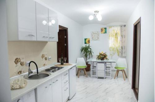 Una cocina con gabinetes blancos y un fregadero y una mesa. en Wall St House, en Sibiu