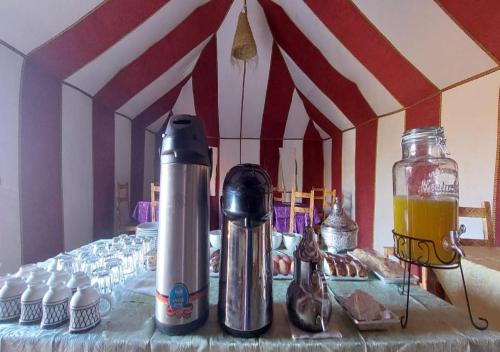 - une table avec 2 thermos et des boissons dans l'établissement Desert Life Camp, à Merzouga