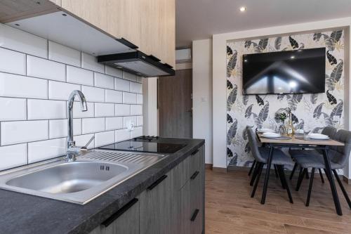 a kitchen with a sink and a table with chairs at Apartamenty Jantar in Łeba