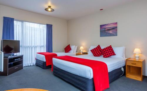 um quarto de hotel com duas camas e uma televisão de ecrã plano em Deans Bush Motel em Christchurch