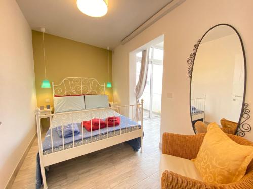 a bedroom with a bed with a mirror and a chair at Penthouse "Maltese scent" in Mellieħa