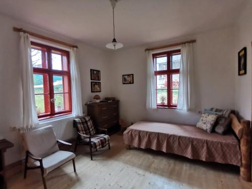 um quarto com uma cama, uma cadeira e janelas em U Páců em Hodslavice