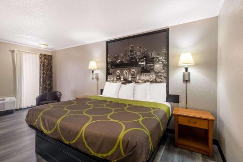 a hotel room with a bed with a yellow and gray bedspread at Super 8 by Wyndham Kansas City Airport North in Kansas City