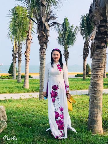a woman standing next to a palm tree at Anh Quân Hotel in Quy Nhon