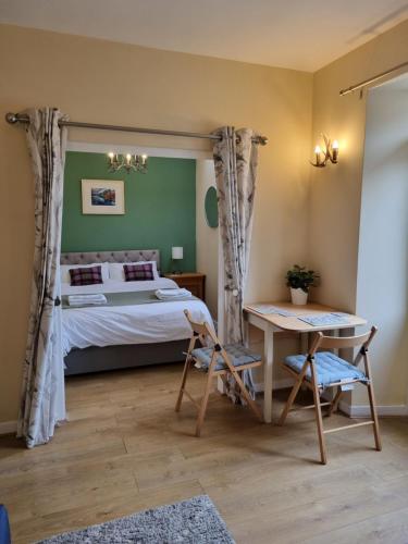 a bedroom with a bed and a table and a desk at Cosy peaceful one-bedroom cottage in Pitlochry in Pitlochry