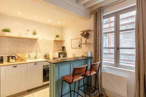 une cuisine avec un îlot bleu et deux tabourets dans l'établissement La Vague - Breath of Freshness in Center of Honfleur - Free Parking 550M, à Honfleur