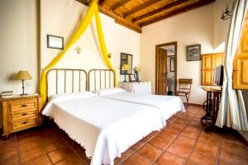 um quarto com uma grande cama branca num quarto em La Hostería de Oropesa em Oropesa