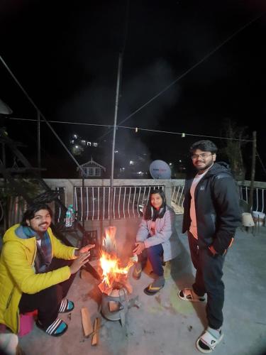 a group of three people standing around a fire at Langdak Homestay in Darjeeling