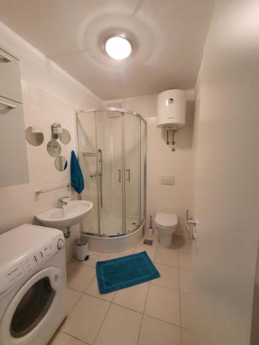 a bathroom with a shower and a sink and a washing machine at Beata East Side apartment in Split