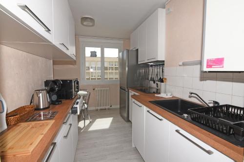 La cuisine est équipée de placards blancs et d'un évier noir. dans l'établissement Le Dieppe Plage appartement Vue Mer, à Dieppe
