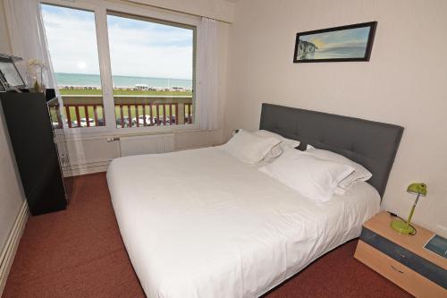 une chambre avec un lit blanc et une grande fenêtre dans l'établissement Le Dieppe Plage appartement Vue Mer, à Dieppe