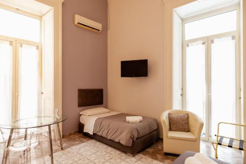 una camera da letto con un letto, un tavolo e una sedia di Suites Trinità in Toledo street a Napoli