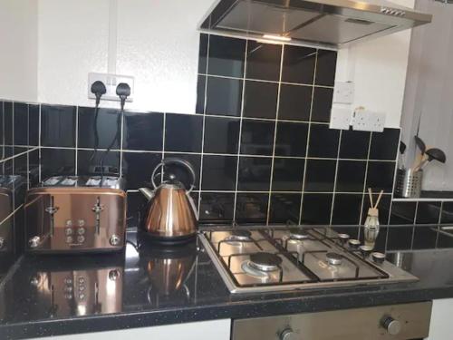 a kitchen with a stove top and black tiles at Kunda House Parkhill in Birmingham