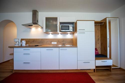 a kitchen with white cabinets and a microwave at Chalet Alpina in Ortisei