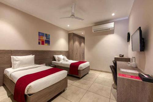 a hotel room with two beds and a television at ROSASTAYS Gurugram Golf Course in Gurgaon