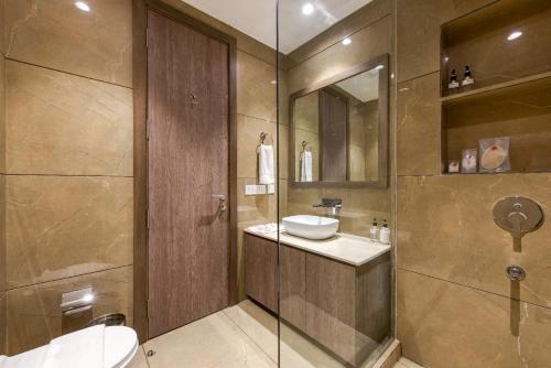 uma casa de banho com um lavatório, um WC e um espelho. em ROSASTAYS Gurugram Golf Course em Gurgaon
