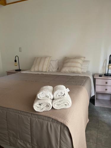 1 dormitorio con 1 cama con toallas en Acceso Bayo - ubicada en el acceso al cerro bayo 3km del centro, en Villa La Angostura