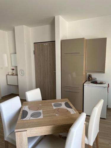 a kitchen with a wooden table and white chairs at Apartment Sunrise with private parking in Pula