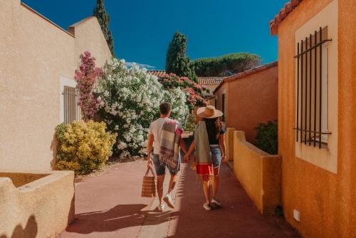a man and a woman walking down a alley at Résidence l'Oustal des Mers in Gruissan
