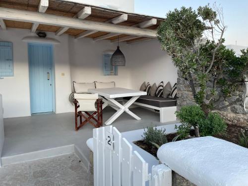 a patio with a white table and a bench at Villa ANASA private Pool & Jacuzzi 8pax at Panormos in Panormos Mykonos