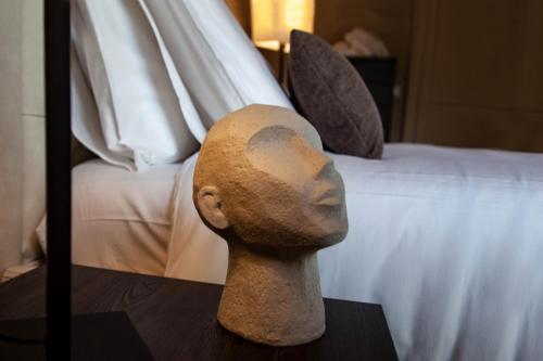 a statue of a head on a table next to a bed at Resort Villa Paola in Longiano