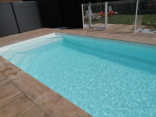 - une piscine d'eau bleue dans la cour dans l'établissement les tourterelles, à Chabournay