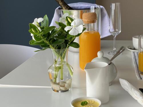 einen Tisch mit einer Vase mit Blumen und Orangensaft in der Unterkunft AT THE SEA Boutique Guesthouse in Swakopmund