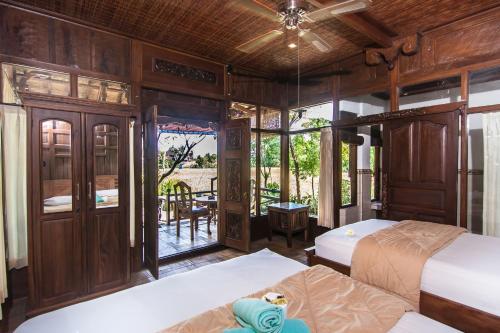 a bedroom with two beds and a balcony at Ganesha Ubud Inn in Ubud