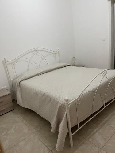 a white bed in a bedroom with a white wall at Emilù a mare in Schiavonea