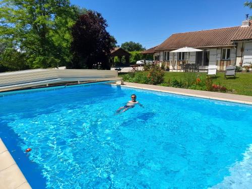 une personne nageant dans une grande piscine bleue dans l'établissement CHAMBRE D'HOTE 40 M2 très agréable, à Mirannes