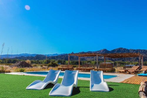 a group of chairs sitting on the grass near a pool at Mini Inca Roca in Uspallata